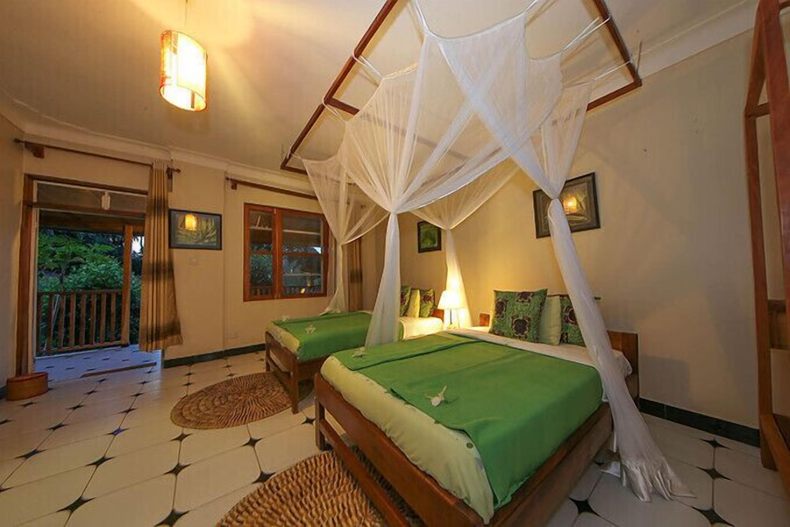 A bedroom with two beds, a mosquito net, and a view of the outside.