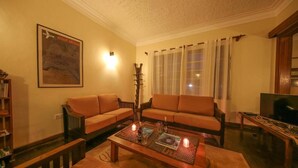 A cozy living room with two sofas, a coffee table with candles, a bookshelf, and a television.