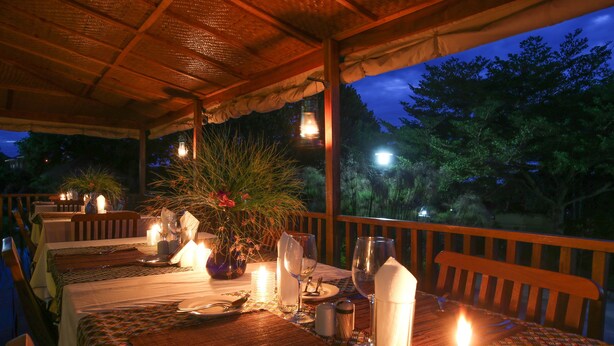 An outdoor dining area with tables set for two, candles, and a view of the night sky.