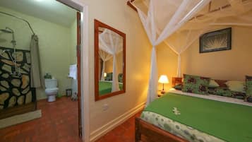 A bedroom with a bed, a nightstand, a bedside table with a lamp, a mirror, and a window with curtains.
