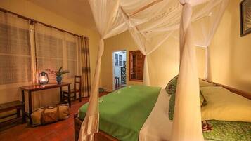 A room with a bed, a table with a lantern, and a chair.