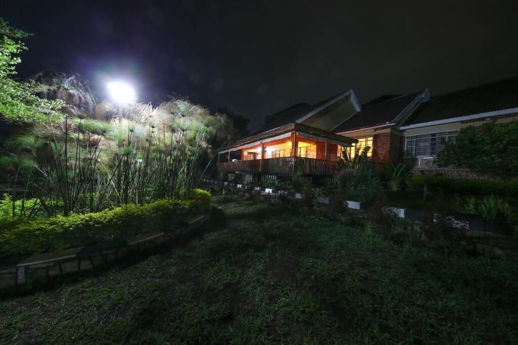 A house with a large porch and a well-lit garden area at night.