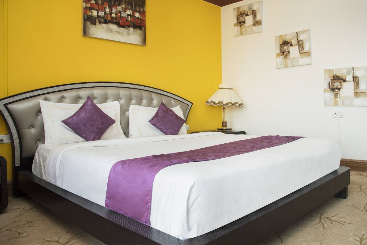 A neatly made bed with a headboard, a bedside lamp, and artwork on the walls.