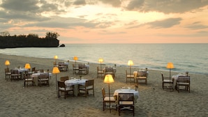 Een restaurant aan het strand met tafels en stoelen, met uitzicht op zee.