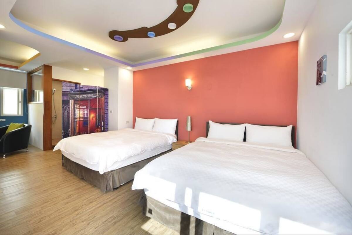 Habitació d'hotel amb dos llits, una paret d'accent vermella i un sostre amb un disseny circular.
