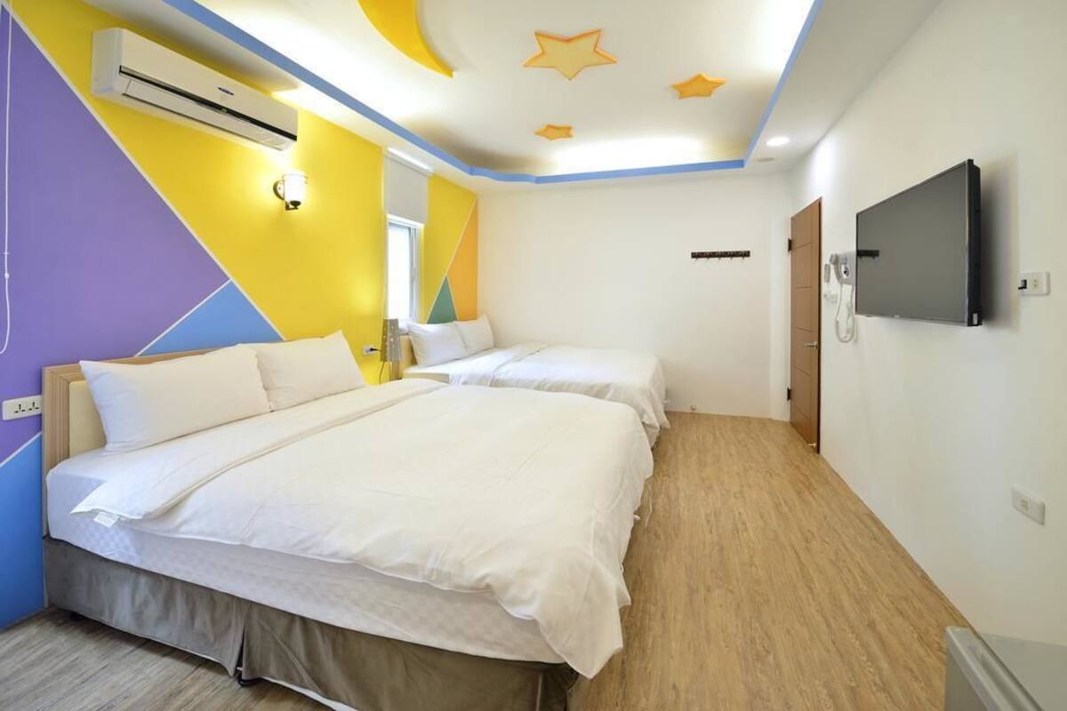 Habitació d'hotel amb dos llits, televisió, aire condicionat i sostre decorat amb estrelles.