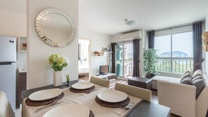 A modern living room with a dining area, a large mirror, and a view of the city.