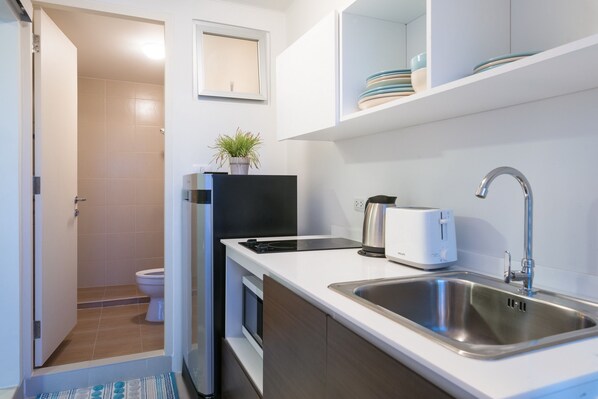 A compact kitchen with a sink, toaster, and a potted plant on the counter. - Baan Kunkoey & KuKeange by Passionata (Hua Hin)