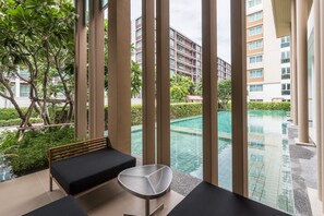 A modern hotel room with a view of an infinity pool, a wooden bench, and a glass table. - Baan Kunkoey & KuKeange by Passionata (Hua Hin)