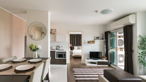 A modern apartment with a dining area, kitchen, living room, and a balcony with a view.