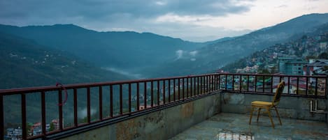 A balcony with a metal railing overlooking a mountainous landscape.
