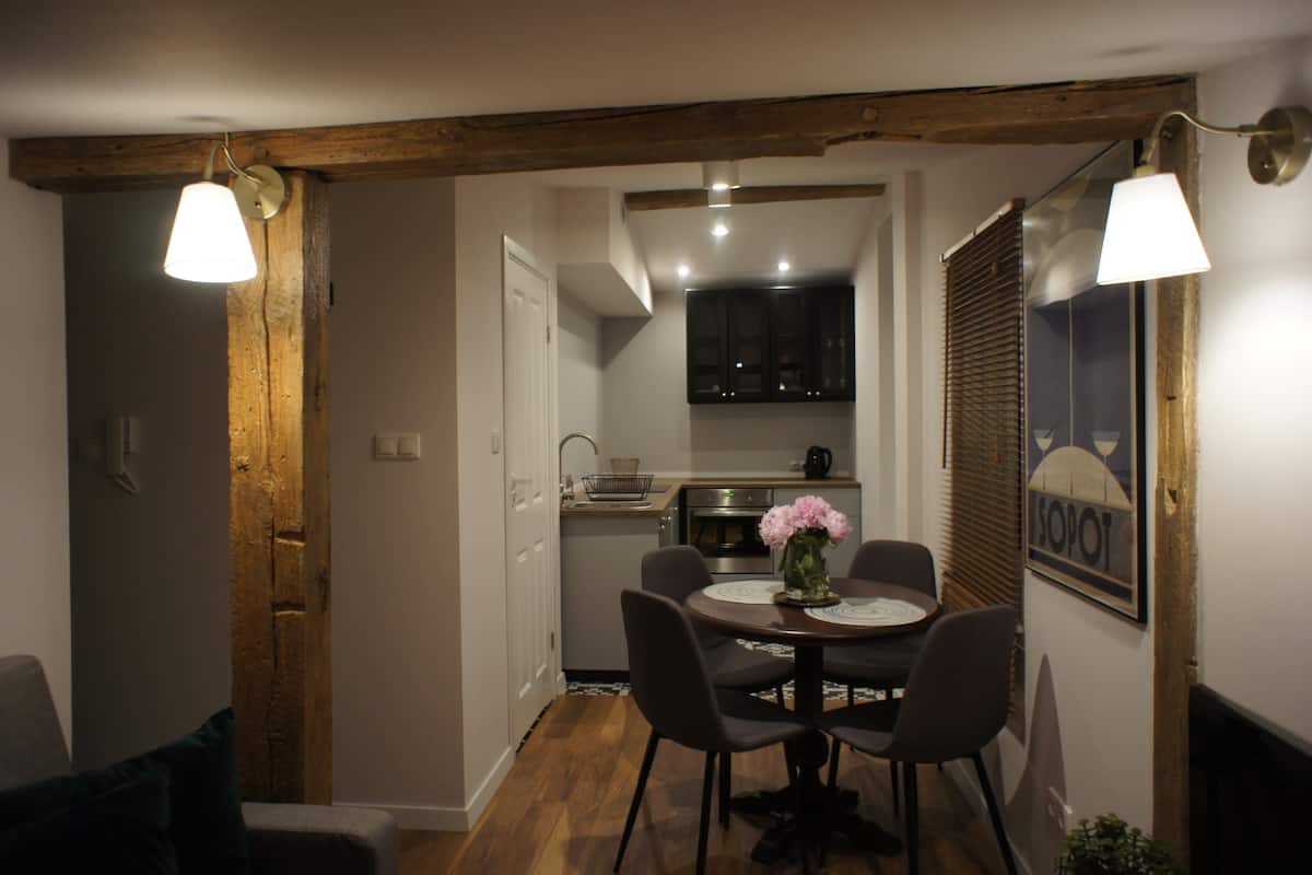 A compact kitchen with modern appliances, a dining area with a table and chairs, and a cozy seating area with a couch.
