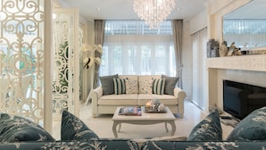 A living room with a sofa, coffee table, chandelier, and a fireplace. - Hua Hin Beach Villa by Passionata (Hua Hin)