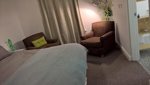 A hotel room with a bed, a chair, and a small table. - Regent Serviced Suites (Doncaster)