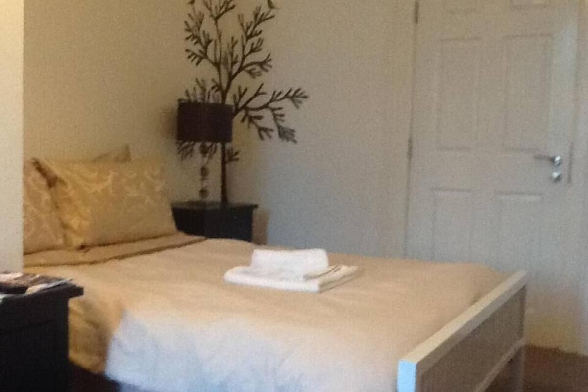 A neatly made bed with a white comforter and a folded towel on top.