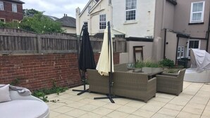 A patio with outdoor furniture, including a round seating area and a table with chairs. - Regent Serviced Suites (Doncaster)