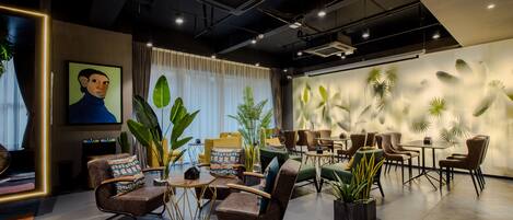 A modern lounge area with comfortable seating, a flat-screen TV, and decorative plants.