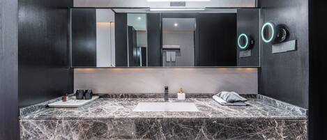A modern bathroom with a large mirror, two sinks, and a marble countertop.