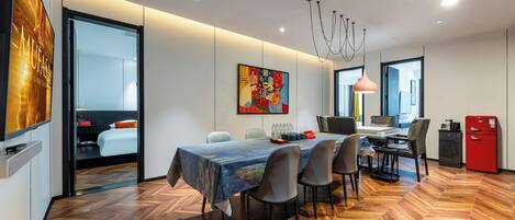 Un comedor moderno con suelo de parqué, una mesa con mantel colorido y un cuadro en la pared.