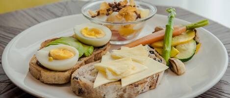 Une assiette avec des toasts, des œufs, des légumes et un petit bol de yaourt agrémenté de granola.