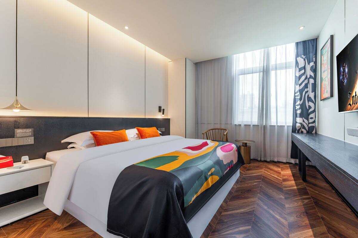 Une chambre d’hôtel moderne, dotée d’un grand lit, d’un bureau et d’une chaise.