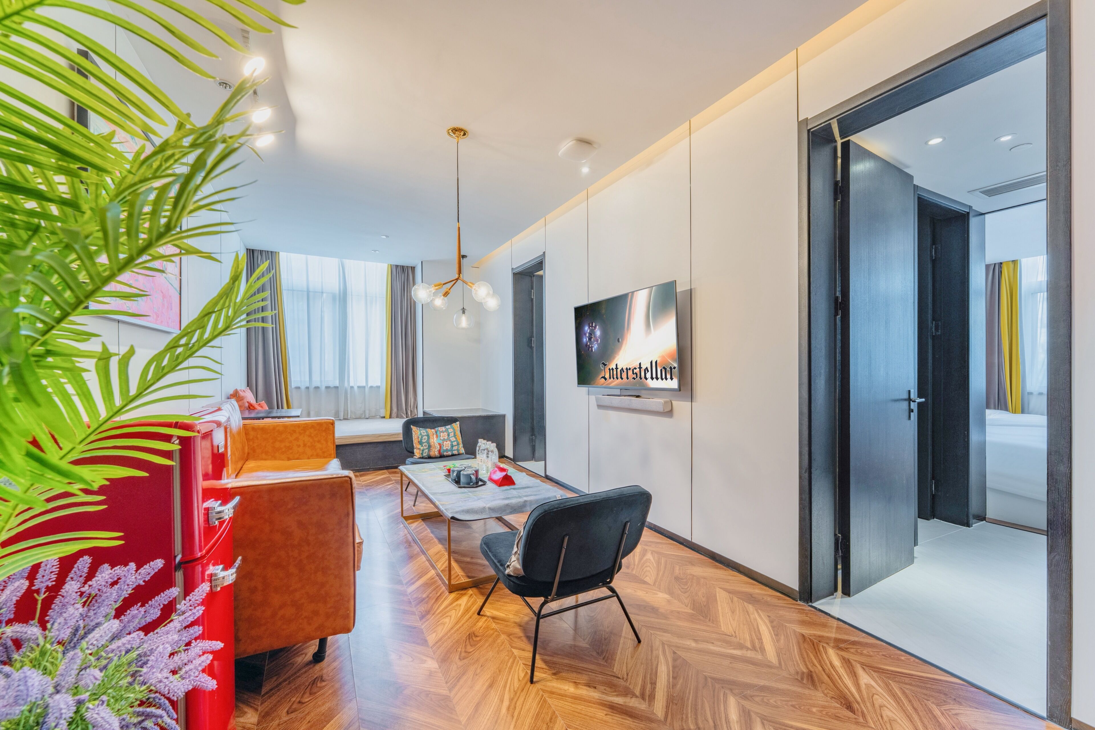 A modern living room with a sofa, a coffee table, a TV, and a red vintage refrigerator.