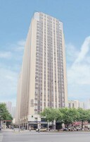 Un hotel alto y moderno con un diseño vertical llamativo, situado en una concurrida intersección urbana con movimiento en la calle y edificios circundantes.