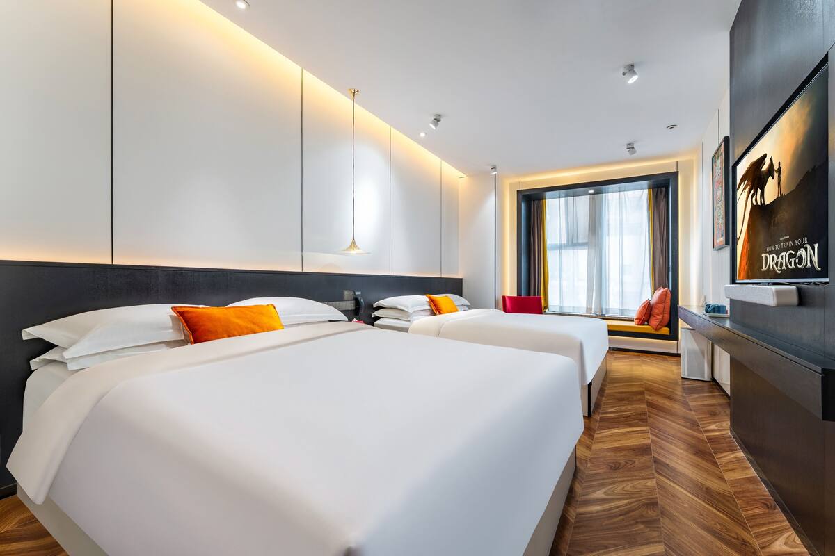 Une chambre d’hôtel moderne avec deux lits, un bureau et une grande fenêtre.