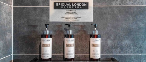 A bathroom with a sign above a shelf displaying three bottles of EPIQUAL London products.