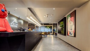 Eine moderne Hotelhalle mit einer Rezeption, einer Treppe und Kunstwerken an den Wänden.