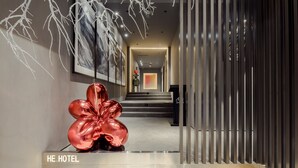 Eine moderne Hotelhalle mit Treppe, einer großen abstrakten Skulptur und einem Schild mit der Aufschrift "HE HOTEL".