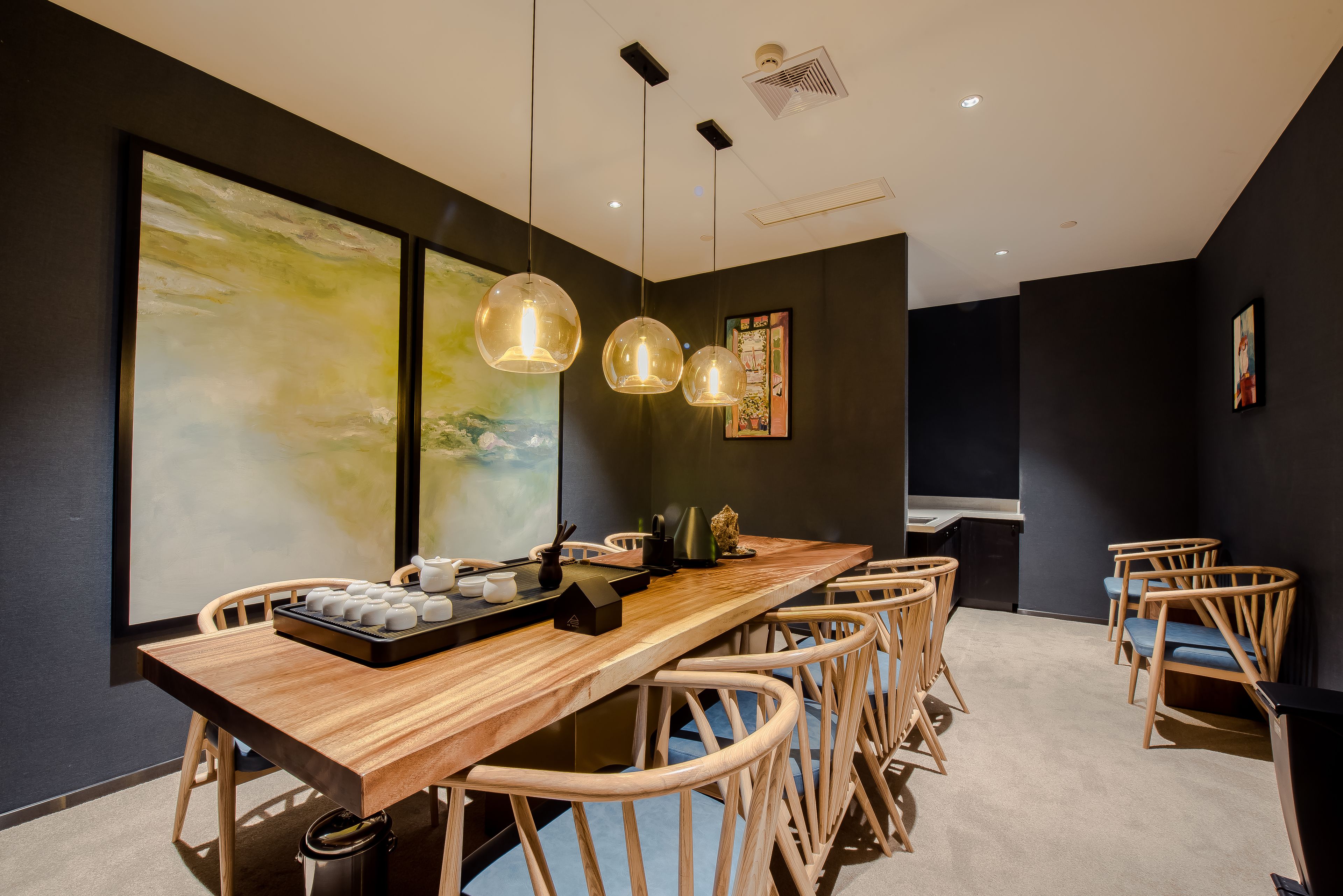 Un comedor moderno con una mesa de madera larga, sillas de mimbre e iluminación colgante.
