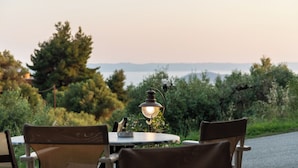 Une table ronde avec deux chaises, une lampe de table et une vue sur un paysage naturel, avec des arbres et un horizon lointain.