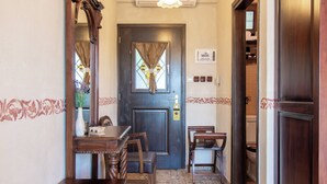 Un hall d’hôtel avec un comptoir d’accueil en bois, des chaises, une porte en bois foncé dotée d’une fenêtre et un sol carrelé.