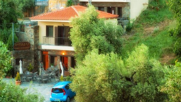 Un quartier résidentiel situé sur une colline, avec des maisons à étages, un café et une voiture garée.