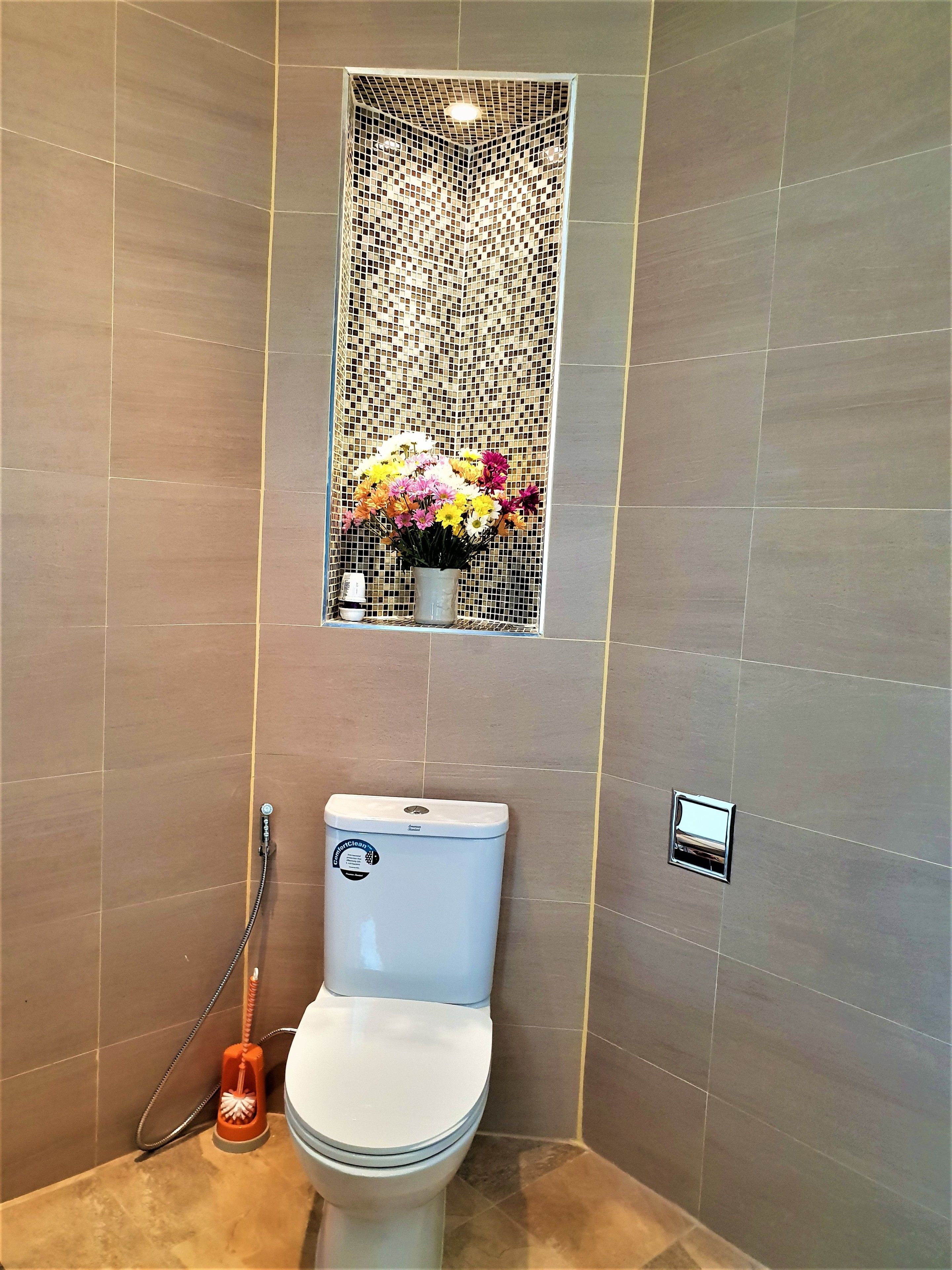 A modern bathroom with a toilet, a shower, and a decorative mosaic wall.
