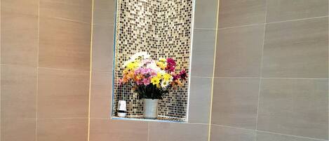 A modern bathroom with a toilet, a shower, and a decorative mosaic wall.