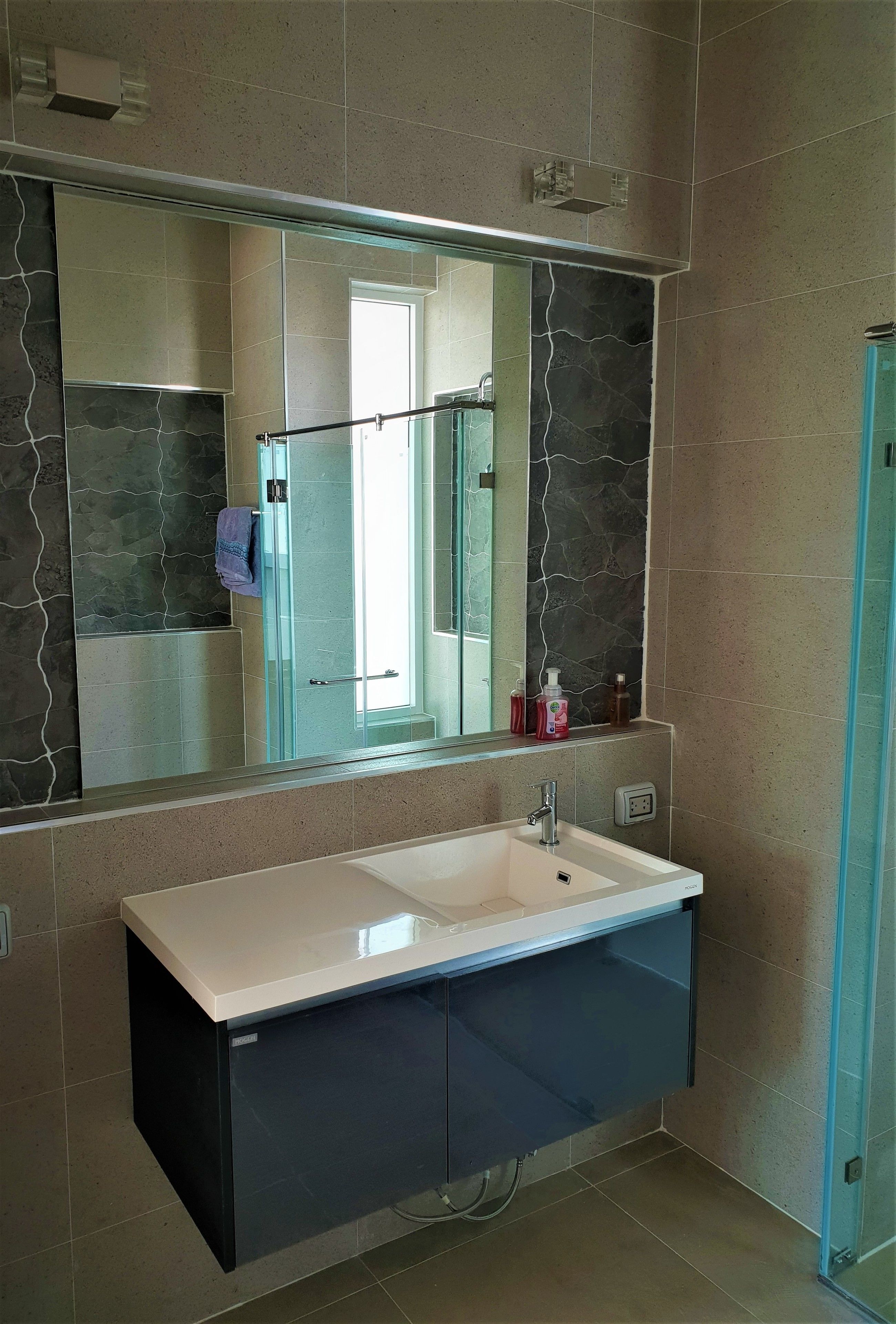 A bathroom with a large mirror, a white sink, and a glass shower enclosure.