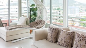 Uma sala de estar moderna com uma cadeira suspensa, um sofá e uma janela grande com vista para a cidade.