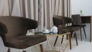Un coin repas moderne avec des chaises à revêtement marron foncé, une table à plateau en verre et un service à thé blanc.