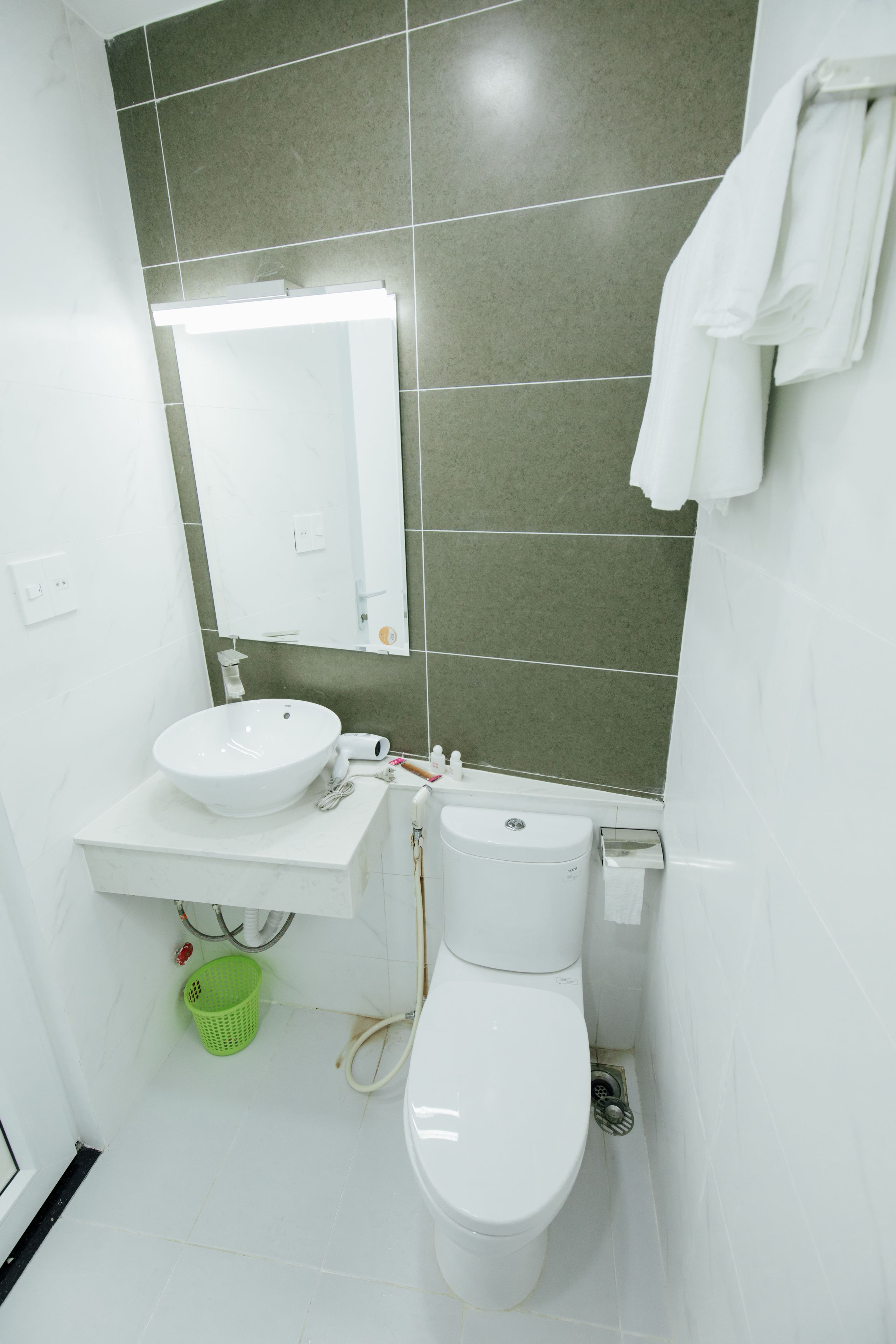 Une salle de bain avec un lavabo blanc, un miroir et des toilettes.