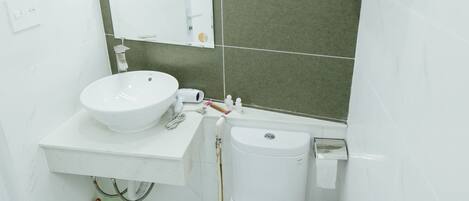 Une salle de bain avec un lavabo blanc, un miroir et des toilettes.
