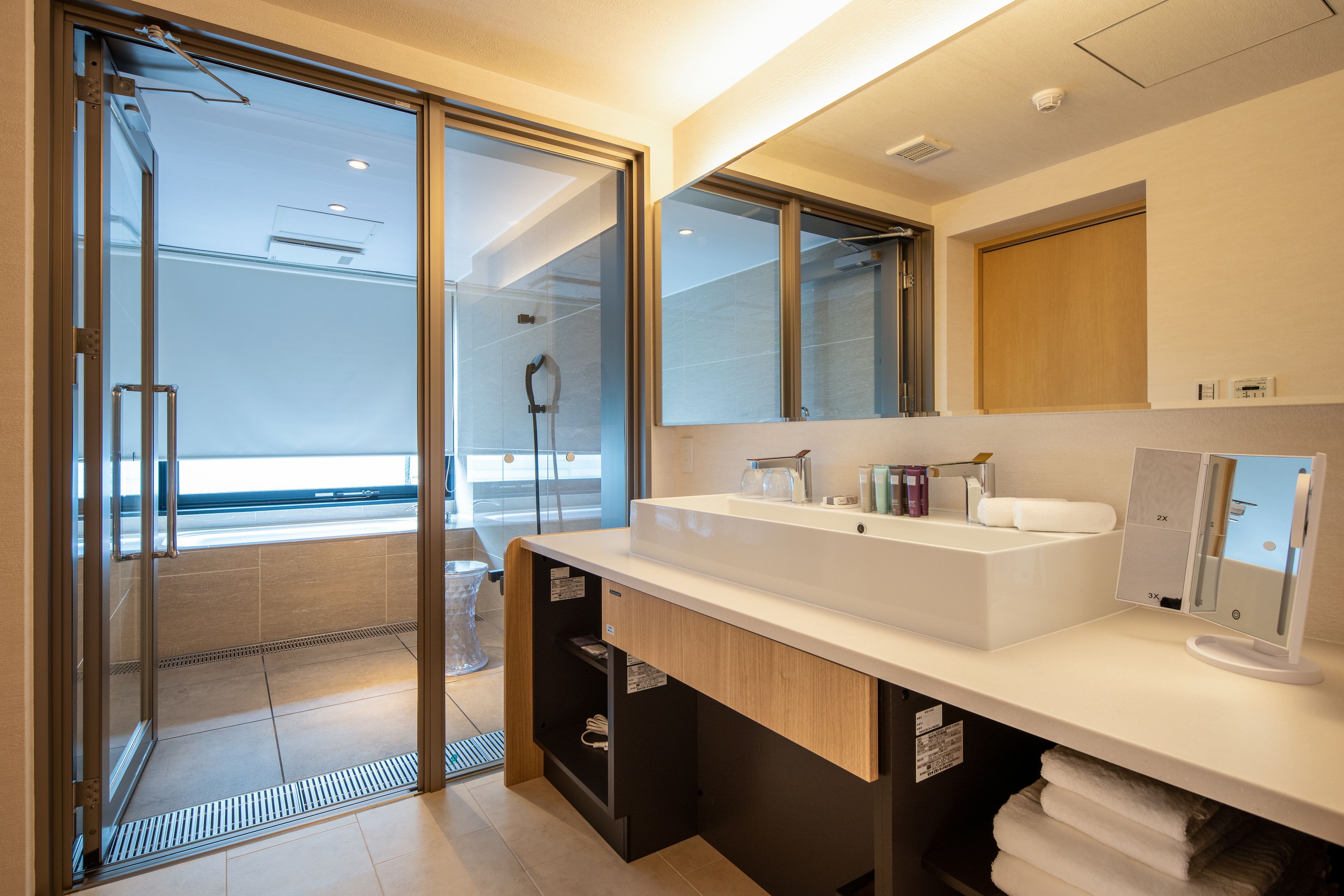 A modern bathroom with a large mirror, a white sink, and a glass shower enclosure.
