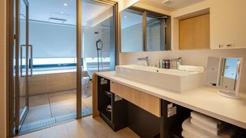 A modern bathroom with a large mirror, a white sink, and a glass shower enclosure.
