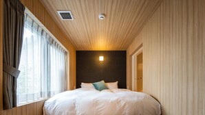 Un dormitorio con una cama grande, una ventana con cortinas, un respiradero en el techo y una lámpara de pared.