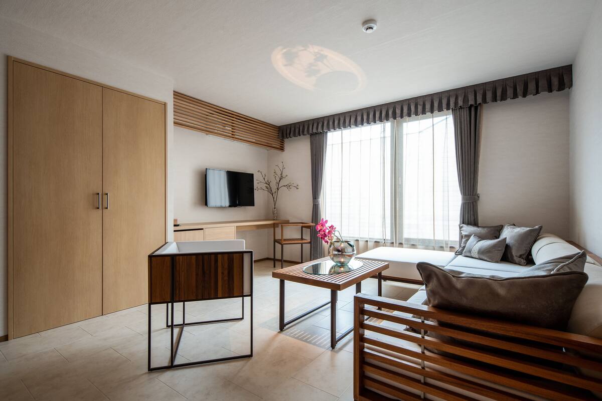 A modern living room with a sofa, a coffee table, and a TV mounted on the wall.