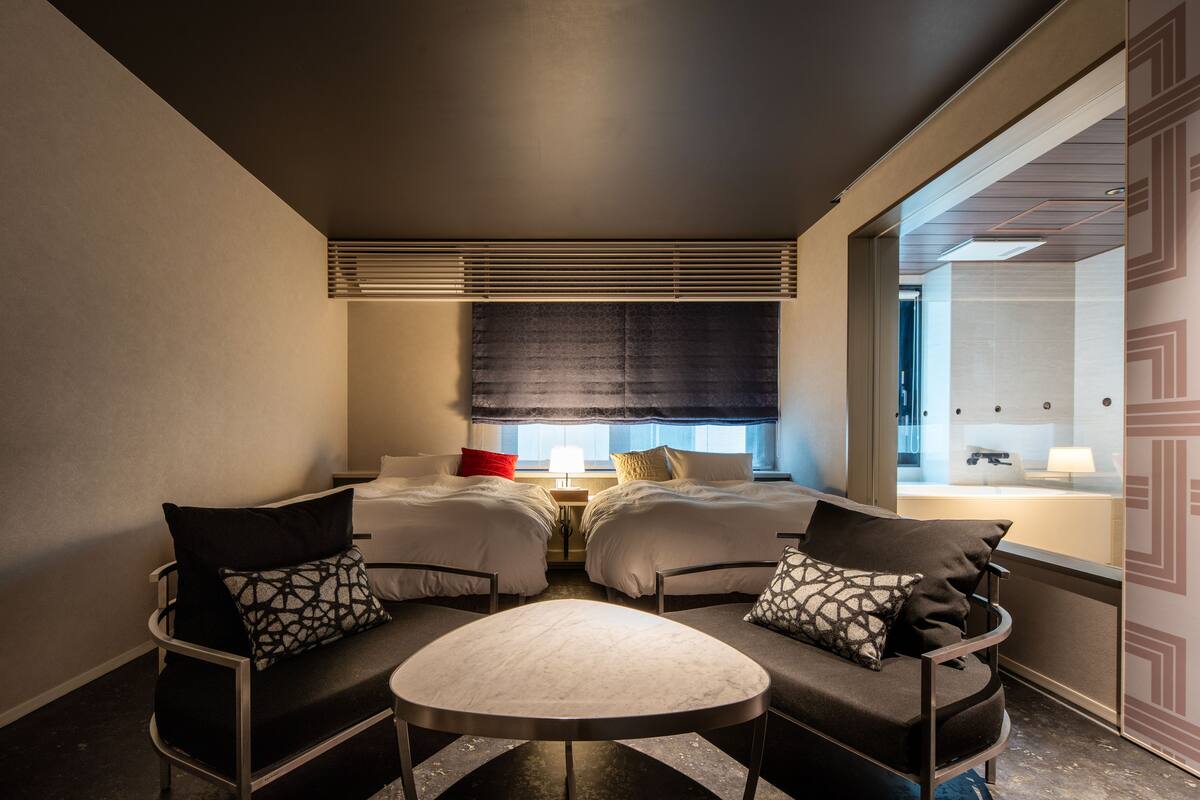 A hotel room with two beds, a small table, and two chairs.