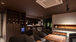 Un interior moderno con mesas y sillas de madera, una zona de cocina integrada y un amplio ventanal con vistas al exterior.