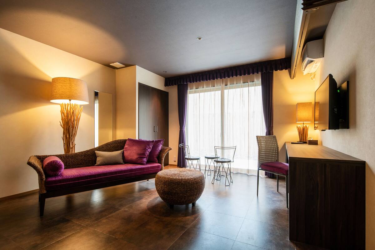 A modern living room with a sofa, ottoman, and dining area.