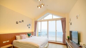 A hotel room with a large bed, a TV, a desk, and a balcony with a view. - Brother B&B (Magong)